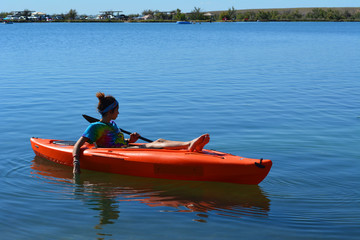 Kayaking Horizontal/Women relaxing in a orange kayak with her feet on the front.