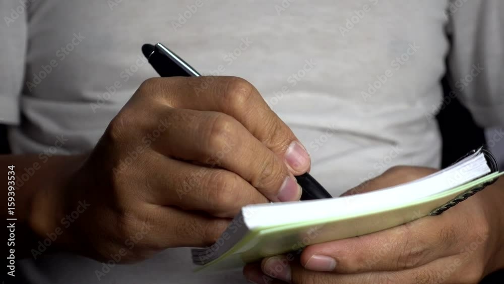 Poster close-up of men hand pen writes in a notebook