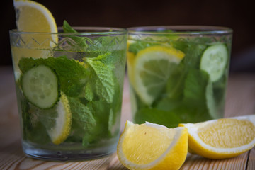 Detox water, fresh organic lemonade with ice, cucumber, lemon and mint on wooden background