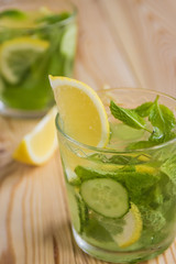 Detox water, fresh organic lemonade with ice, cucumber, lemon and mint on wooden background