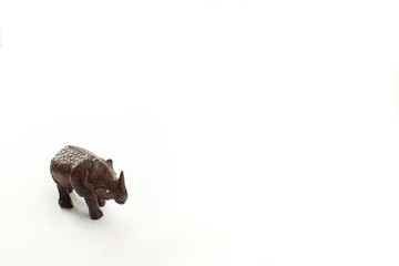 Close up of hand carved wooden rhinoceros standing looking down isolated on white background 