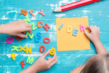 Children play plastic letters to combinations word "IDEA" .
