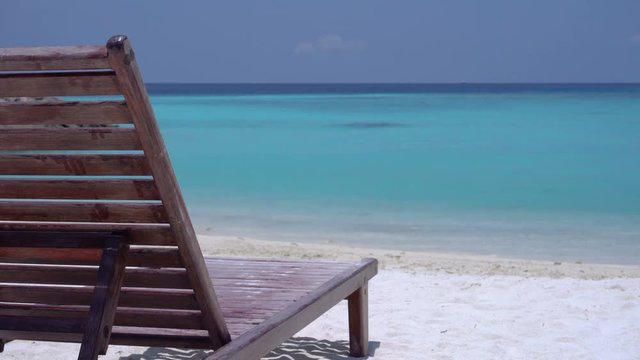 One wooden sunbed on tropical calm beach with turquoise sea water and white sand

