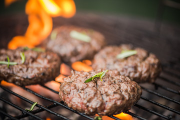 BBq meat burgers over charcoal flames