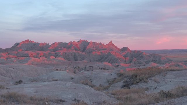 AERIAL: Beautiful reddish sandstone mountaintops in Badlands National Park at sunset. Stunning sunrise above eroded rocky mountain formations in S Dakota, United States