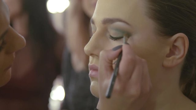 Makeup artist makes a girl beautiful makeup before  photo shooting