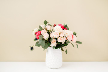 Beautiful flowers bouquet in flowerpot in front of pale pastel beige wall. Floral lifestyle composition.
