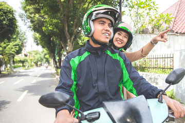 Naklejka premium motorcycle taxi driver taking his passenger to her destination