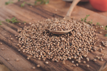 dried coriander seeds on wooden spoon and on wooden cutting board