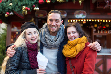 Freunde, Mann, Frau, Paar haben Spaß auf dem Weihnachtsmarkt, lachen, scherzen, trinken Glühwein mit Alkohol und freuen sich in Winterbekleidung