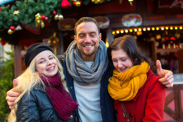 Freunde, Mann, Frau, Paar haben Spaß auf dem Weihnachtsmarkt, lachen, scherzen, trinken Glühwein mit Alkohol und freuen sich in Winterbekleidung