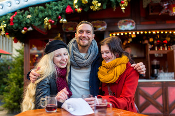 Freunde, Mann, Frau, Paar haben Spaß auf dem Weihnachtsmarkt, lachen, scherzen, trinken Glühwein mit Alkohol und freuen sich in Winterbekleidung