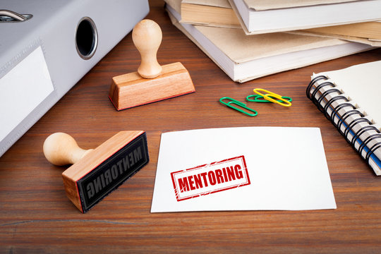 Mentoring concept. Rubber Stamp on desk in the Office.