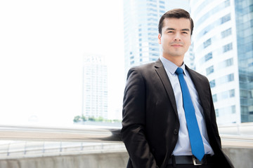 Fototapeta premium Handsome hispanic businessman standing on blur office building background