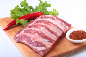 Raw pork ribs with herbs and spices on wooden board. Ready for cooking.