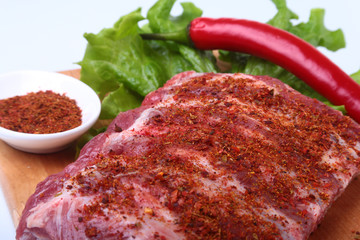 Raw pork ribs with herbs and spices on wooden board. Ready for cooking.