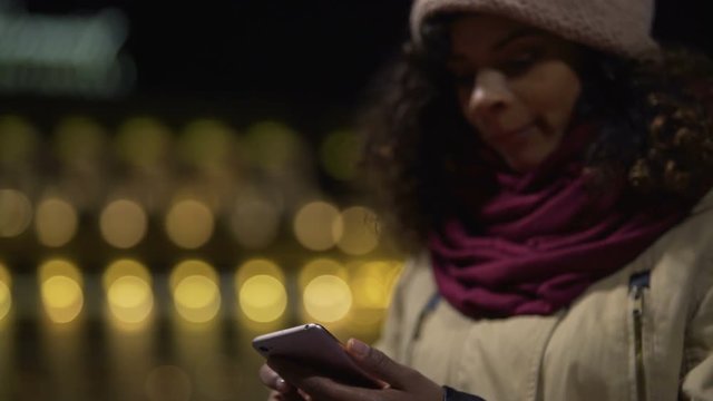 Young woman watching social media newsfeed and waiting for friends outdoors