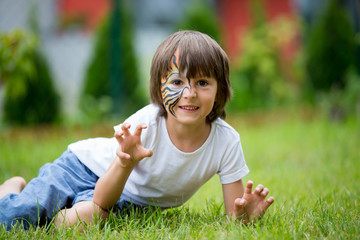 Fototapeta na wymiar Sweet preschool child, painted as tiger, playing in garden