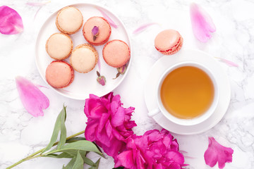 Tea time. Flat lay over light background with peonies, macaroons and cup of tea