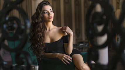 Obraz premium The image of a beautiful luxurious woman sitting on a vintage couch