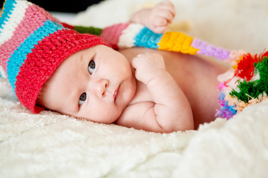 Beautiful two-month-old girl in a red hat. Close-up portrait