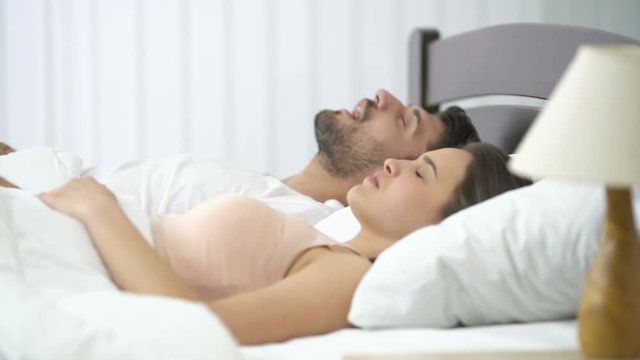 The man snore near the woman on the bed