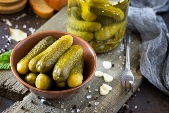 Marinated cucumbers gherkins. Pickles with mustard and garlic on a stone background.