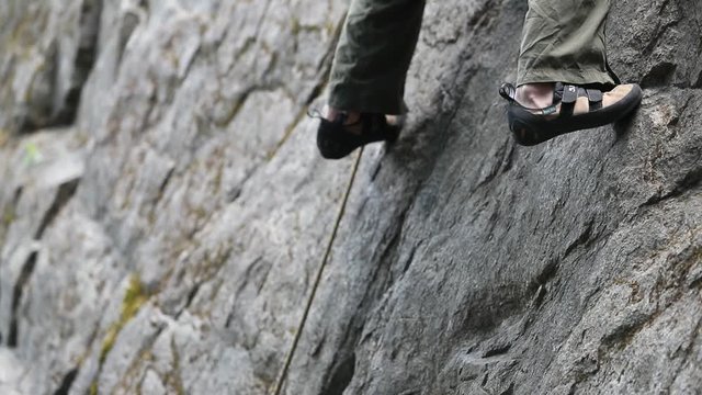Rock climbing detail of climbers shoes on straight vertical wall. Slow motion 120fps detail close up. Extreme risk outdoor sport. Patagonia Argentina.