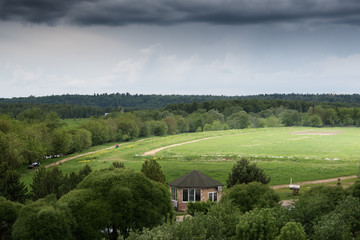 Naklejka premium Green field with river under the dark cloudy sky