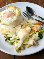 Stir-fried mixed vegetables with tofu and fried egg with rice in white dish on wooden background.  Vegetarian Food, healthy food.