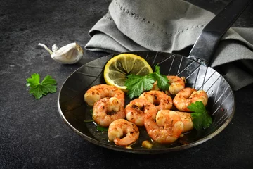 Crédence de cuisine en verre imprimé Crustacés prawns shrimps with garlic, lemon, spices and italian parsley garnish in a black pan on a dark slate plate