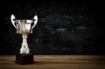 low key image of trophy over wooden table and dark background