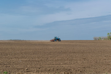 An old tractor in the field plows the land. Spring landscape of a countryside, a farm.