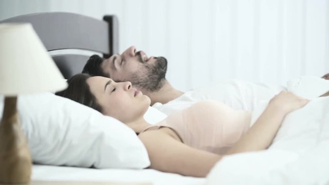 The man sleeping and snore near woman on the bed