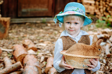 Happy little child girl with cute rabbit. Portrait of kid with pet in village