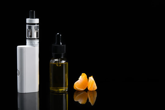 Set for vaping with orange flavor in bottles, on a dark background