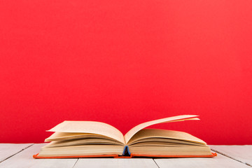 education and wisdom concept - open book on wooden table, color background
