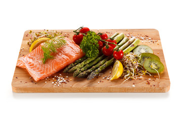 Fresh raw salmon with asparagus on cutting board on white background