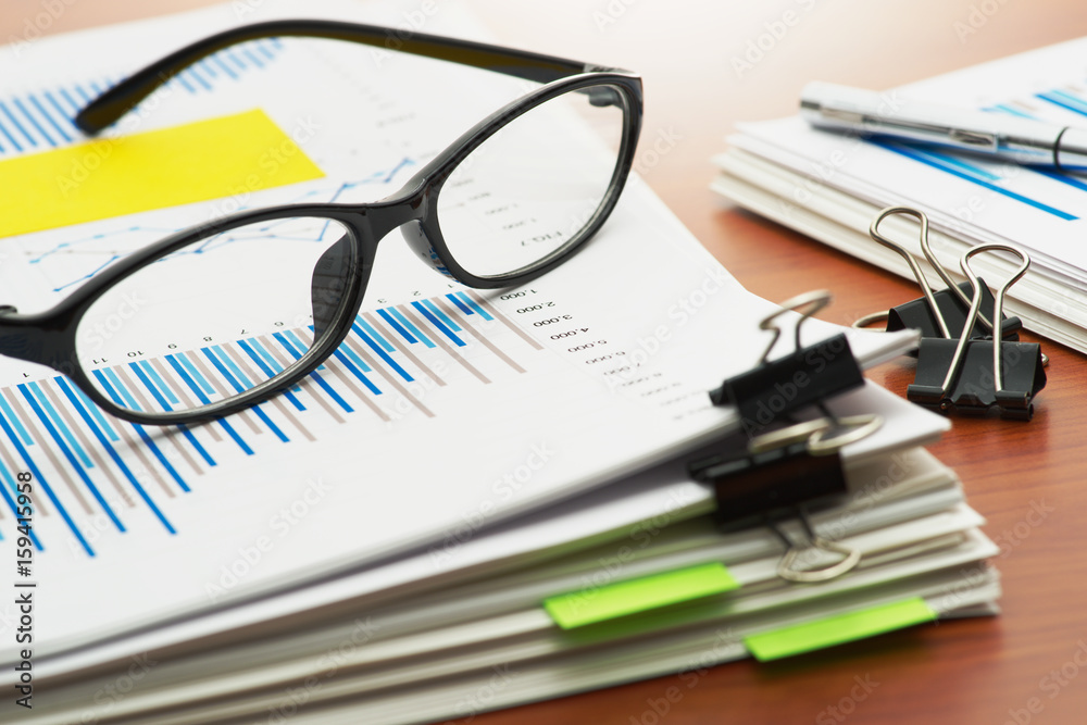 Poster paperwork. pile of documents. scanning reports. pile of documents with blue chart and glasses on woo