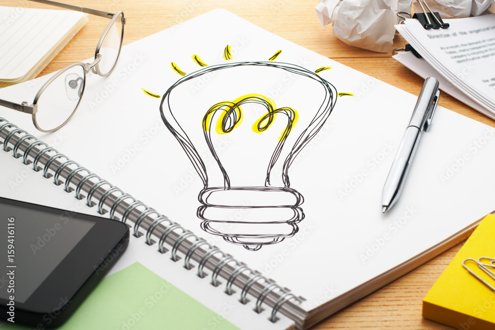 Poster turning on the light bulb. drawing light bulb on notebook. creating ideas. notebook, pen, smartphone