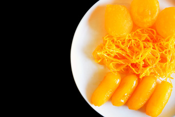 ancient Thai Dessert, thai sweet dessert in bowl on black background,egg yoke fudge balls cooked in syrup, Pinched gold egg yolks, appetizer