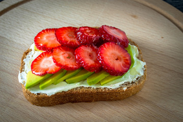 Delicious toast with avocado, strawberries, cheese cream, honey