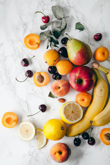 Summer fruits assorted on white marble background. Fresh raw food concept.