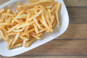 ready for eat french fries putting in dish putting on wooden table are background. this image for food and snack concept