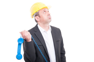 Architect looking bored playing with telephone receiver on shoulder