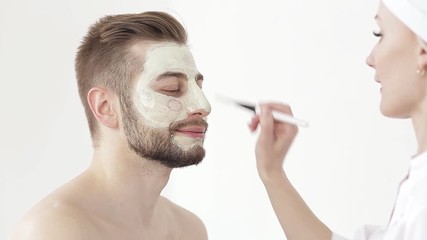 Cosmetologist Care for the skin of the face young man. man receiving a facial treatment application