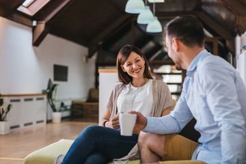 Happy young couple sitting on sofa at home, smiling.