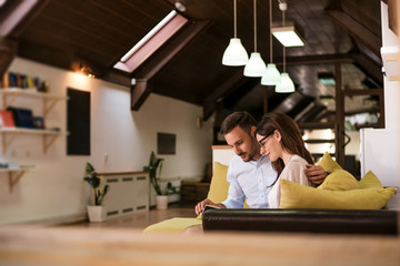 Happy couple reading book, relaxing at home.