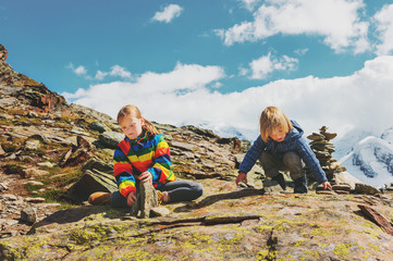 Cute little kids resting in Gornergrat glacier, Switzerland, Two young children playing together in mountains, small boy and his big sister hiking in swiss Alps, wearing colorful clothes