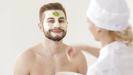 Cosmetologist Care for the skin of the face young man. man receiving a facial treatment application